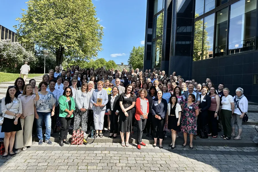 En gruppe mennesker som poserer for et bilde utenfor en bygning