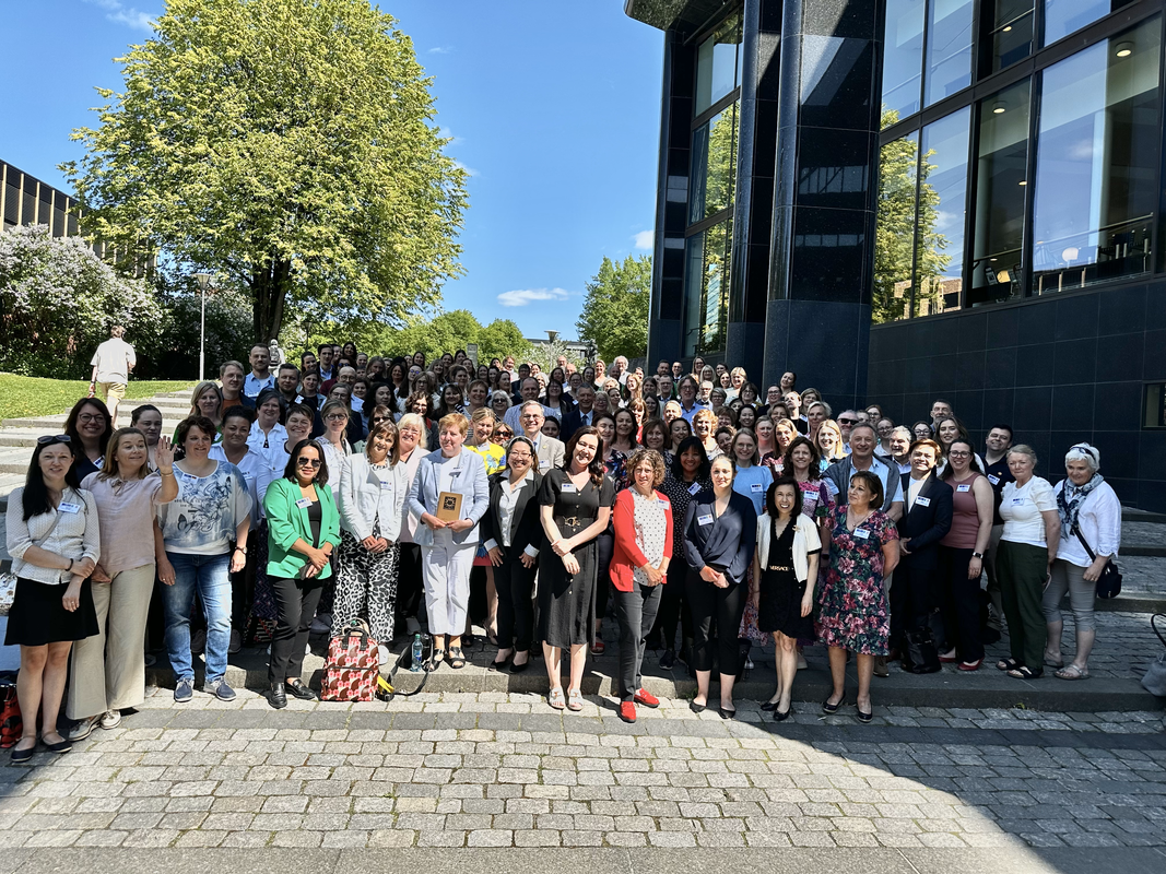 En gruppe mennesker som poserer for et bilde utenfor en bygning