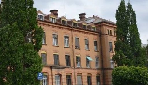 En stor bygning med trær foran seg