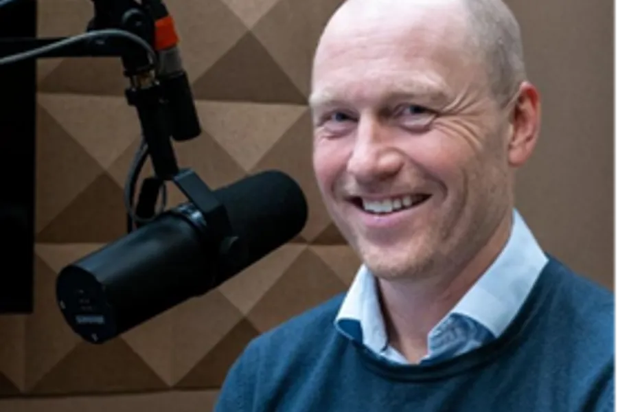 En mann som smiler med et kamera på skulderen