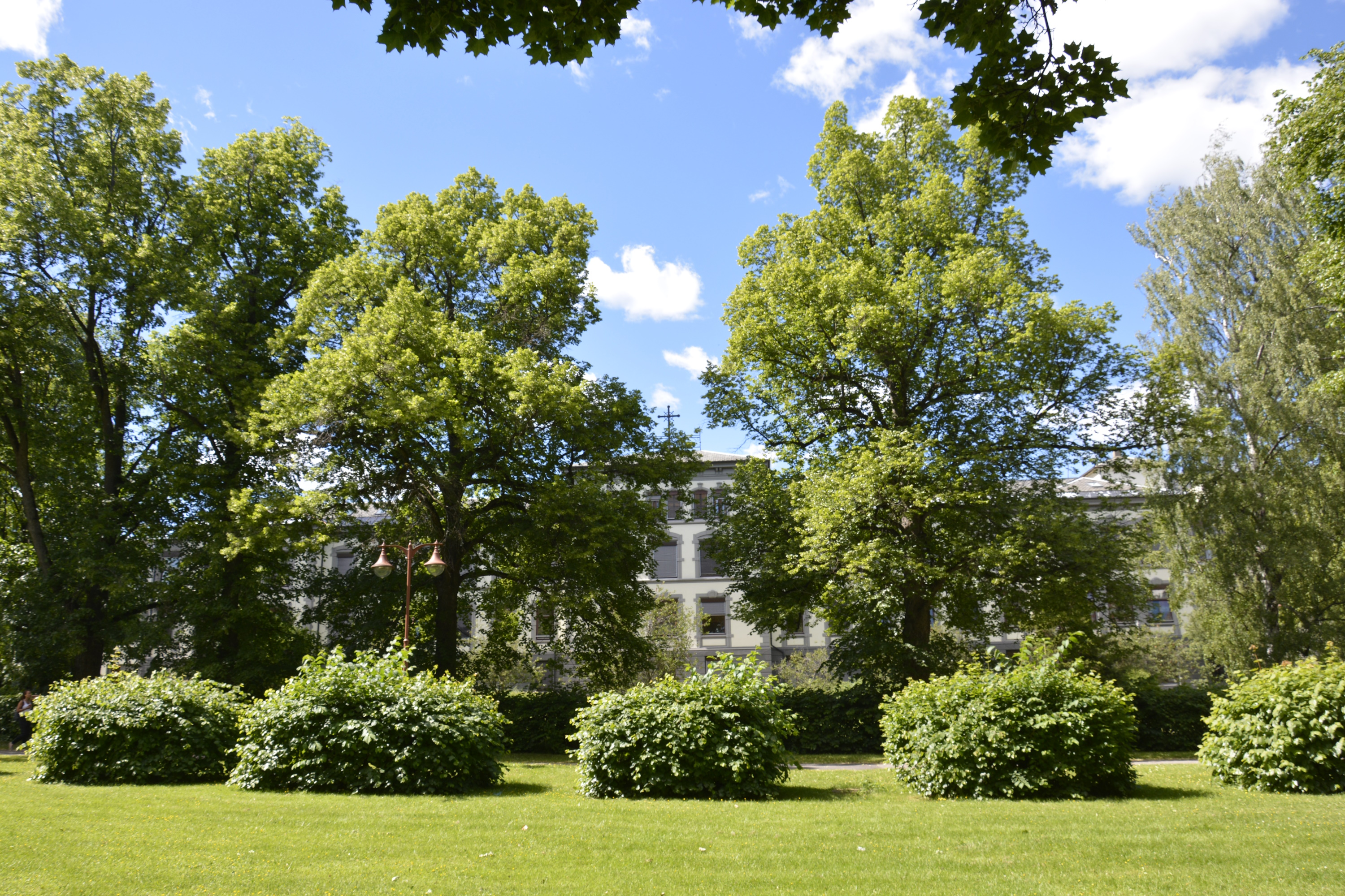 En stor bygning med trær og busker foran seg