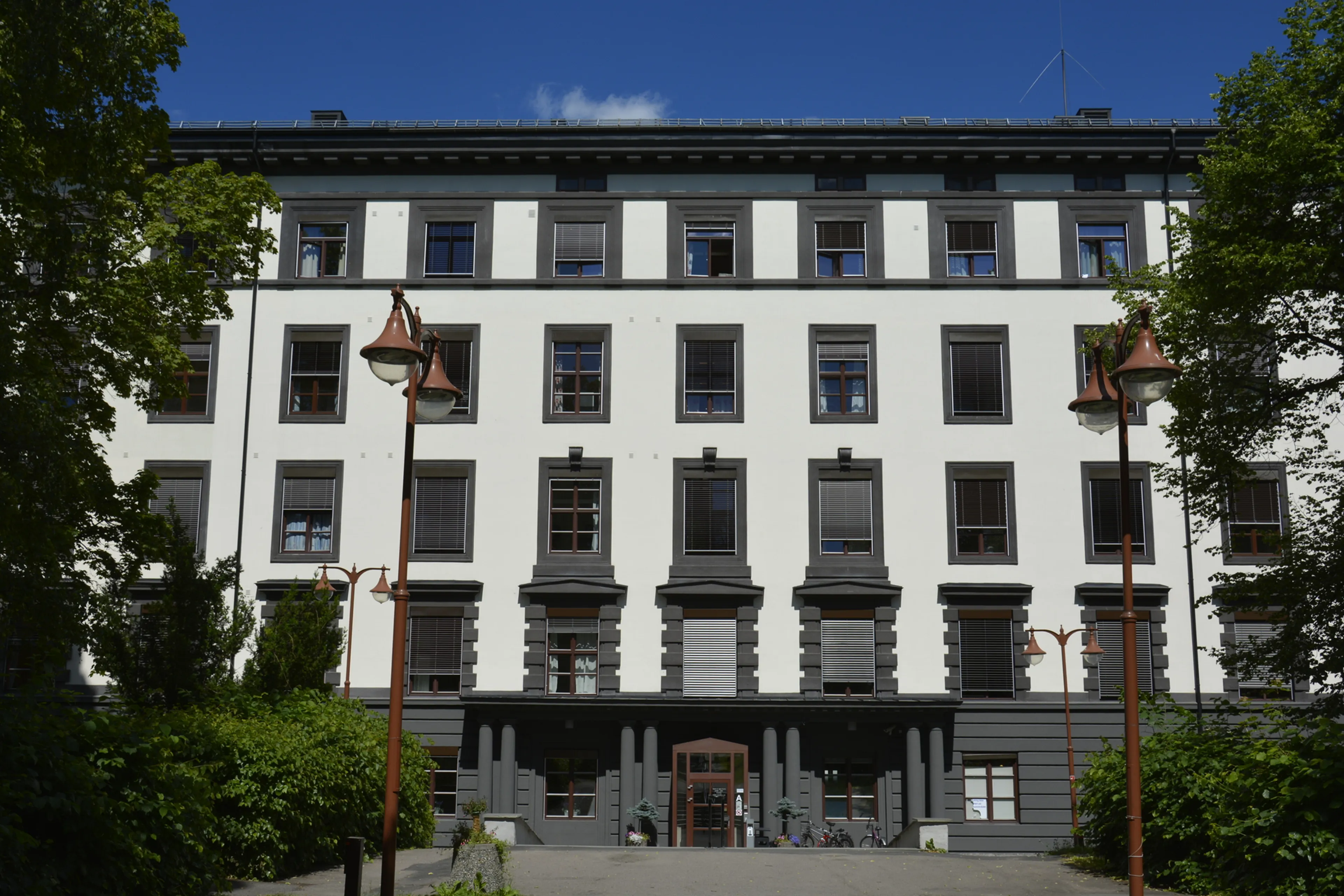 En hvit bygning med trær foran