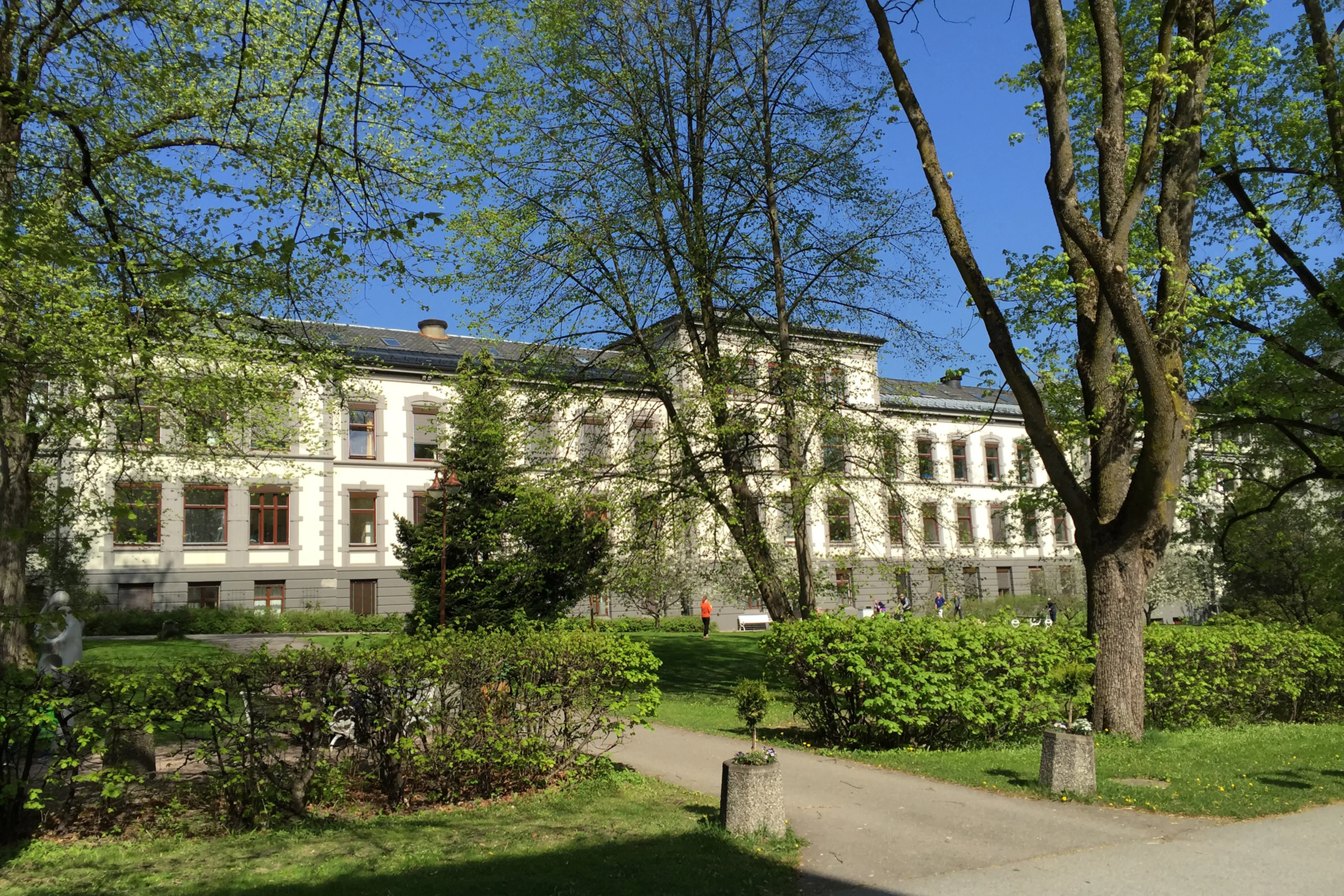 En stor hvit bygning med trær foran