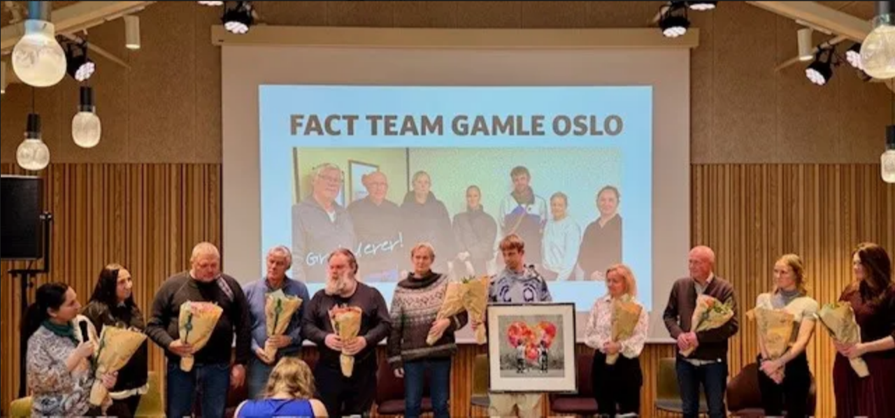 En gruppe mennesker som står foran en stor skjerm