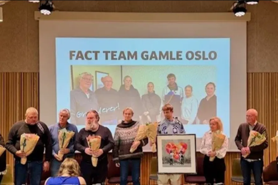 En gruppe mennesker som står foran en stor skjerm