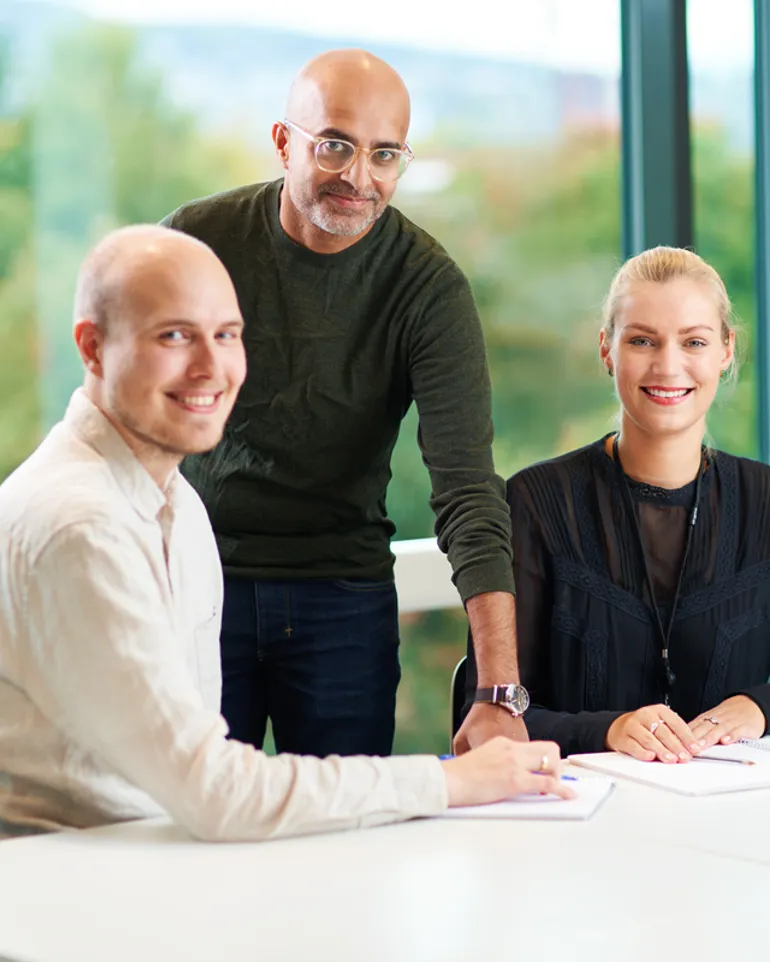 Noen få personer som står ved siden av et bord